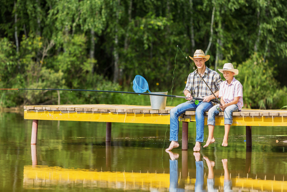 Father and son sitting on bridge and fishing Father and son sitting on bridge and fishing